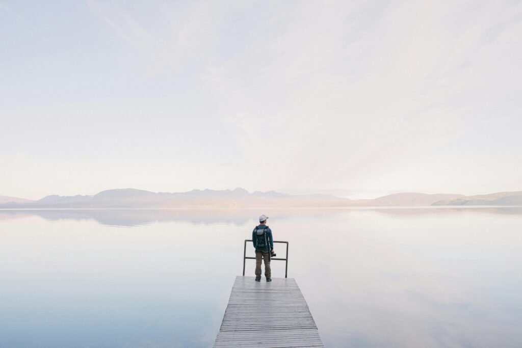 pexels-photo-571169-571169 A solitary traveler stands on a dock enjoying the serene water view