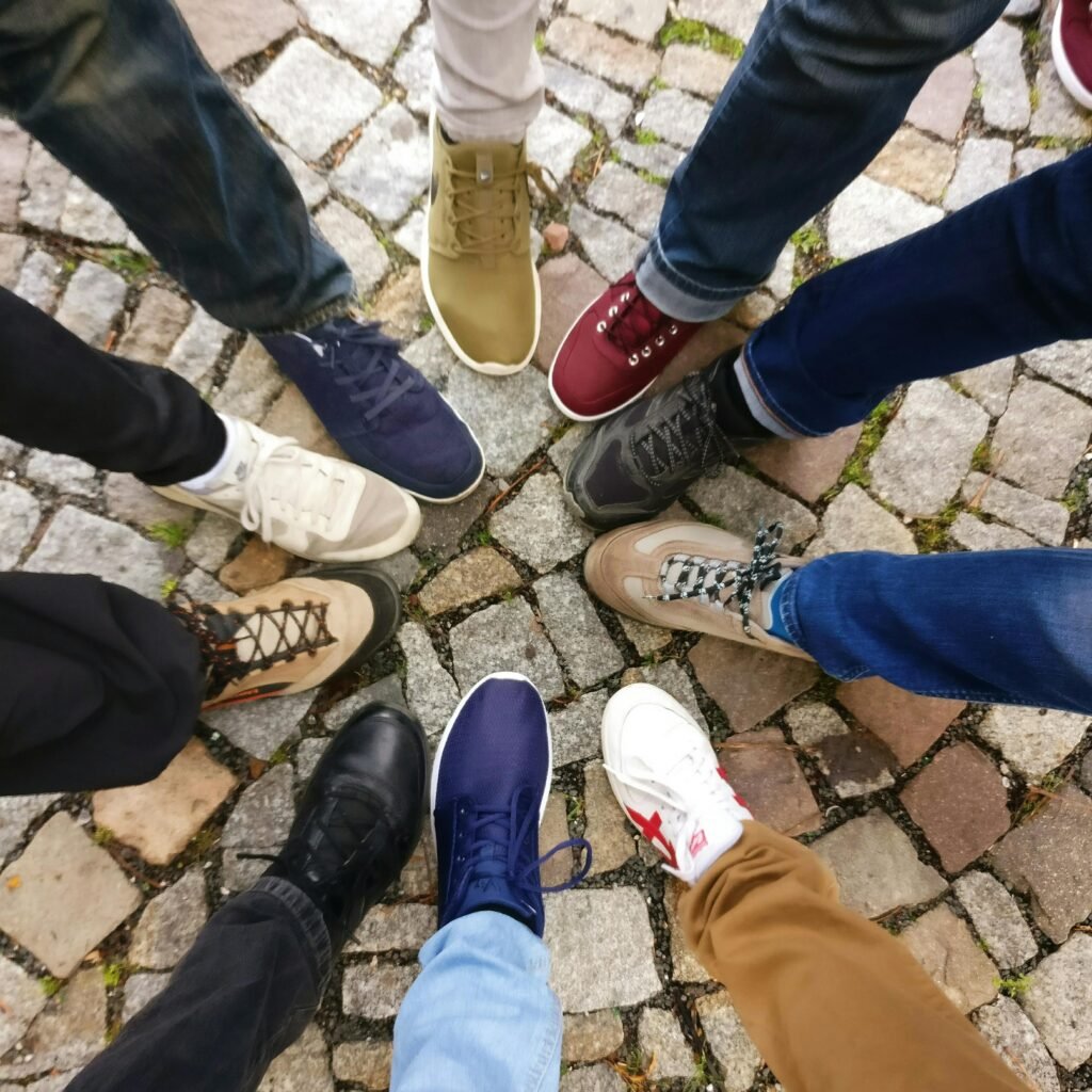 pexels-photo-609771-609771 Circle of sneakers on cobblestone pavement representing diversity and urban fashion.